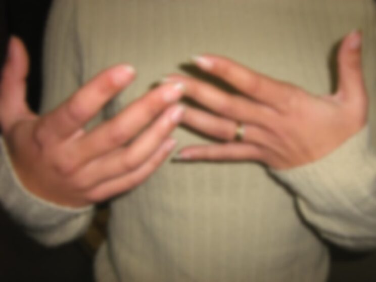 A young woman's hands held close to her body. She appears to be gesticulating as if in conversation.